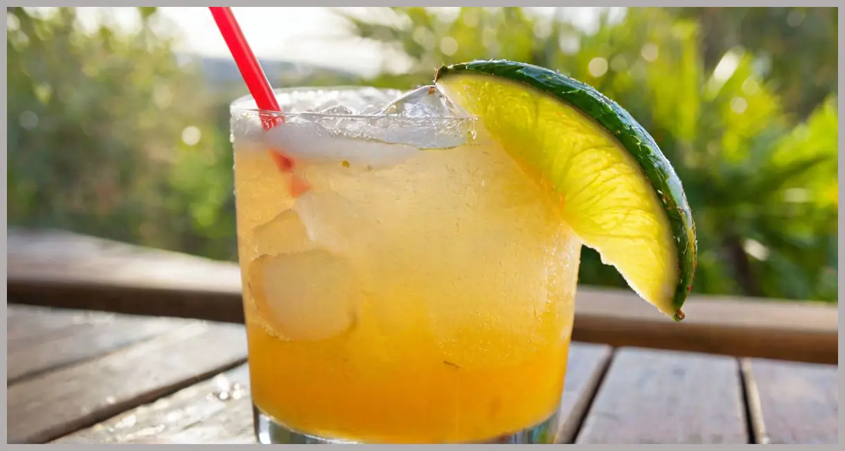 A photorealistic extreme close-up of a frosty highball glass filled with a vibrant Ginger Mango Mule Cocktail, adorned with mango and lime, under warm golden hour light.