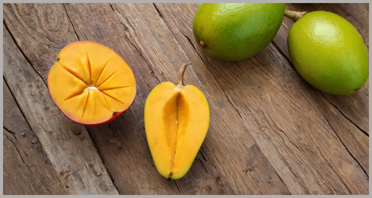 A photorealistic eye-level wide shot of a halved, ripe mango and a piece of fresh ginger root, surrounded by lime halves, under soft studio light, key ingredients for a Ginger Mango Mule Cocktail.
