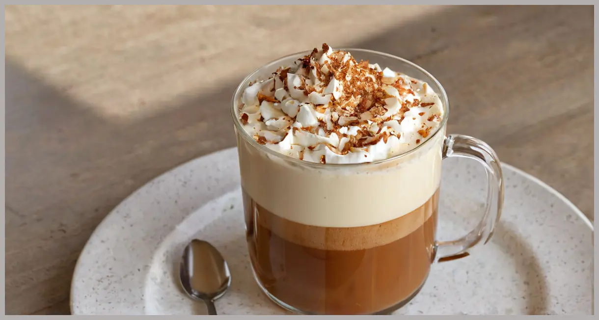 An exquisite Nutella and cognac coffee cocktail Cocktail in a clear Irish coffee mug, featuring distinct layers of dark coffee, creamy whipped double cream, and toasted coconut flakes, bathed in warm golden hour light.