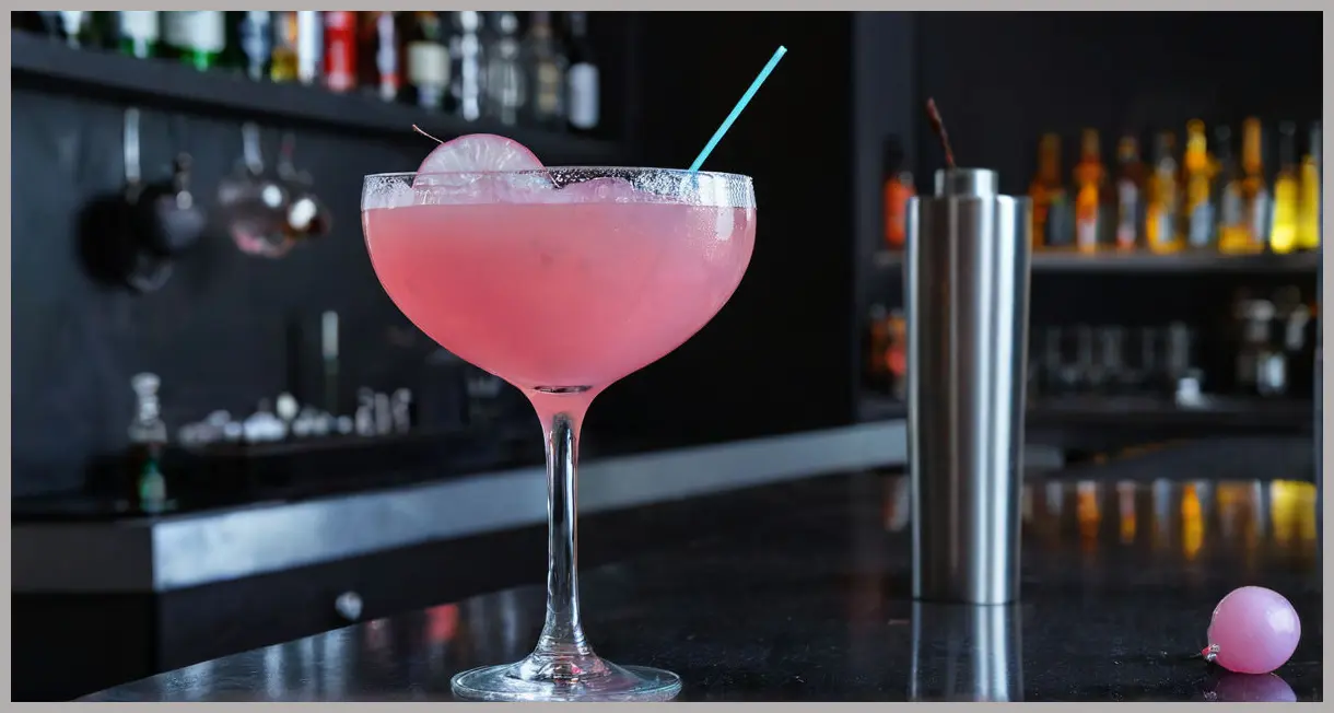 A photorealistic image of a Pink Gibson cocktail in a condensation-beaded martini glass on a sleek black bar, bathed in a mysterious cool neon glow.