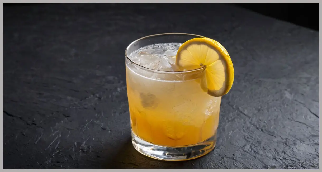 A medium close-up, photorealistic image of an Umibozu yuzu cocktail Cocktail in a chilled coupe glass on a dark slate coaster, featuring a lemon twist garnish, under dramatic, moody side lighting.