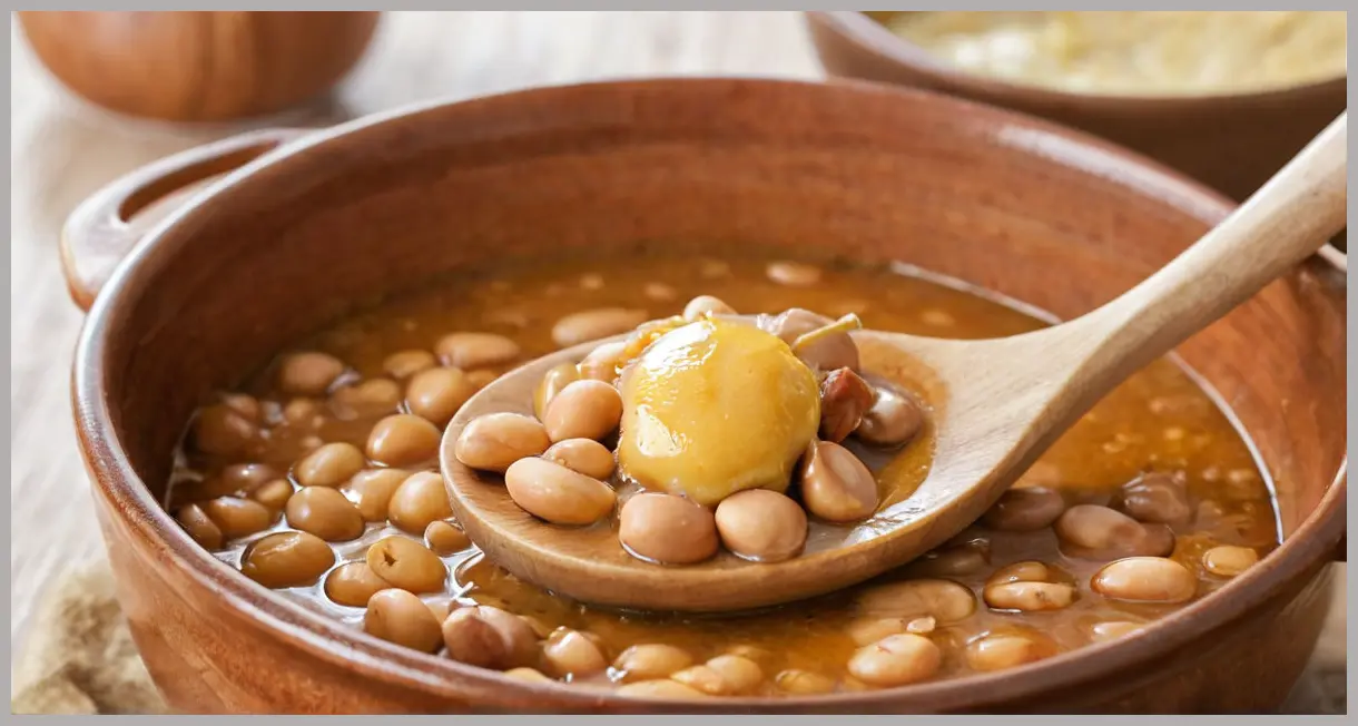 Vegan sausage casserole details: a butter bean and chestnut on a wooden spoon, glistening with gravy, macro shot in natural daylight.