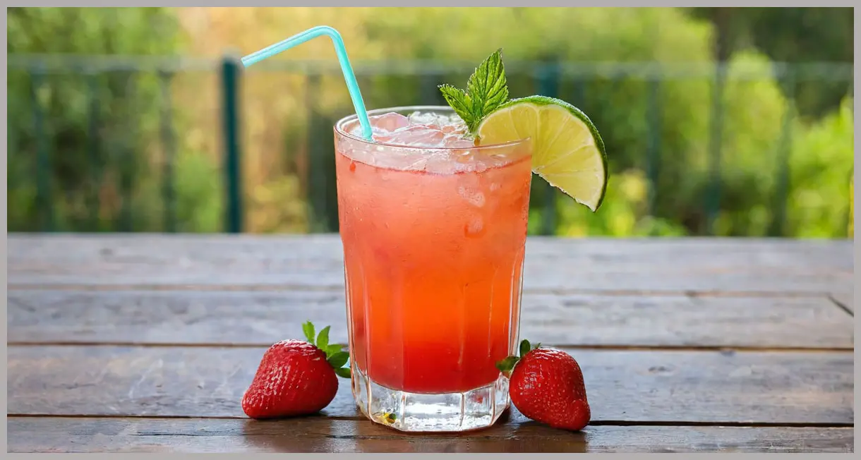 A photorealistic close-up of a Strawberry, lime and elderflower muddle in a tall highball glass, garnished with mint and lime, bathed in warm golden hour light on a wooden surface.