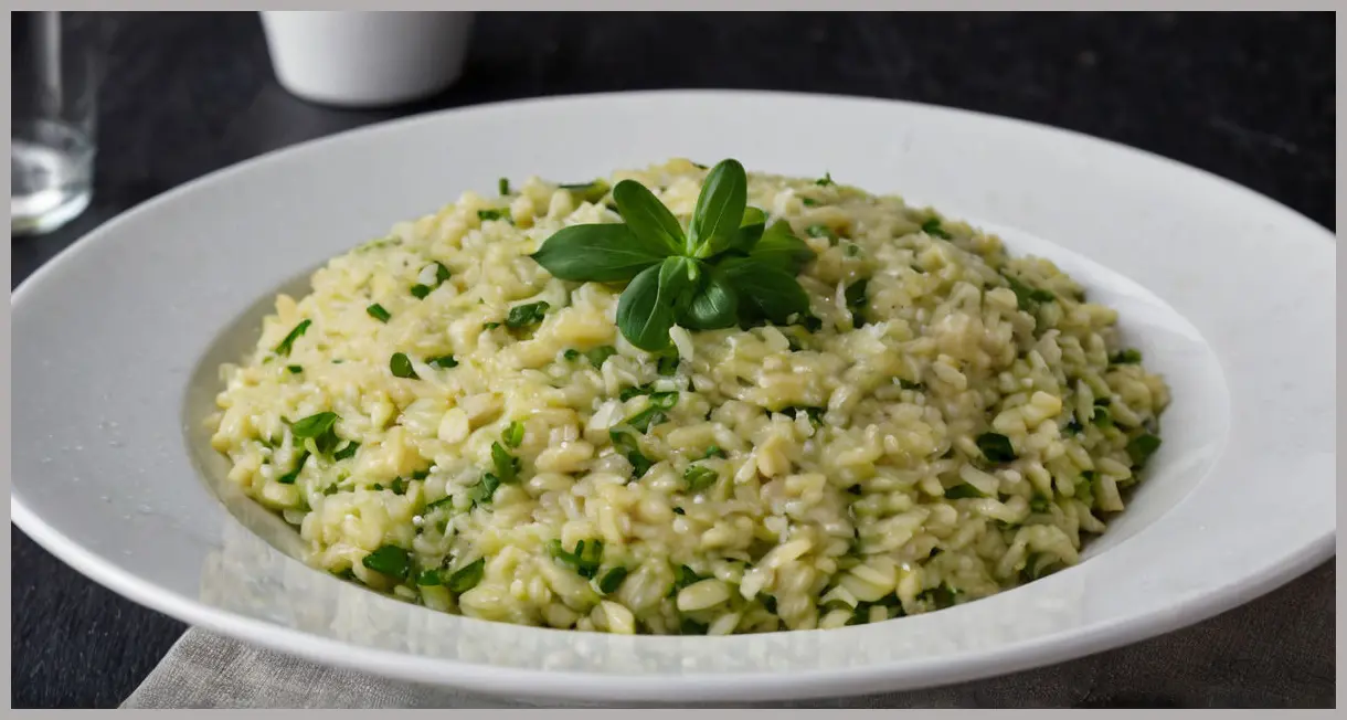 Close-up of leek and watercress risotto in a white bowl, swirled with green puree. Garnished with almonds and olive oil, set against a dark background.